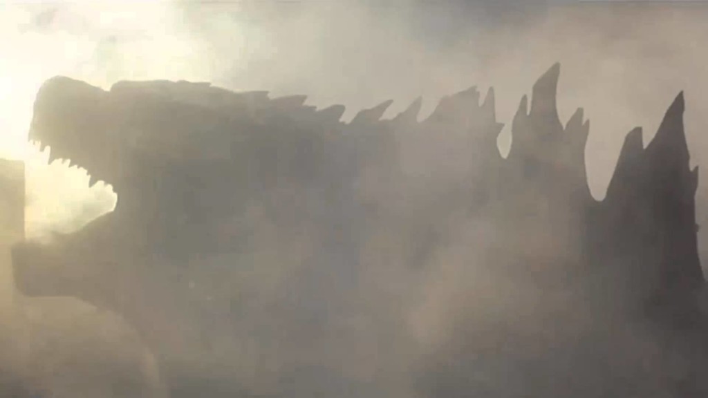 La sagoma di Godzilla tra il fumo e la polvere delle macerie che ha causato